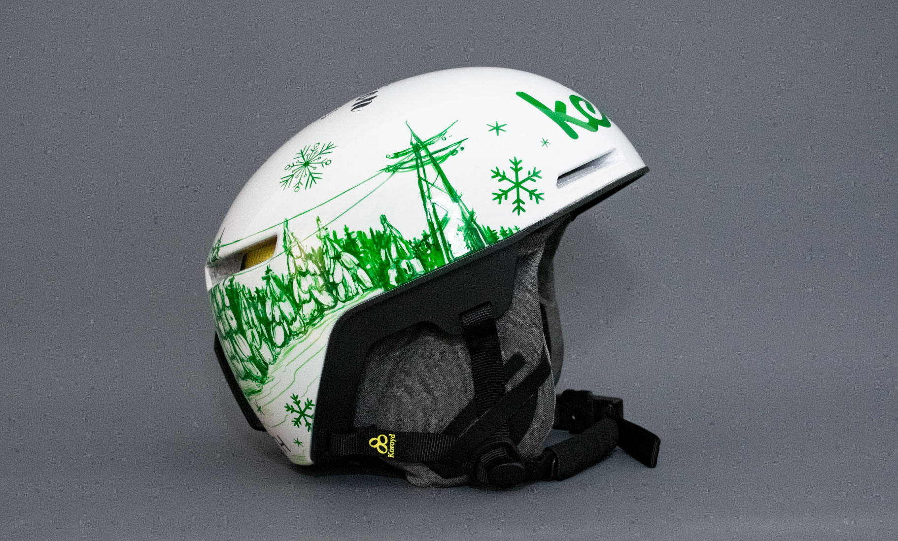 weißer Skihelm mit grün gezeichnetem Aufdruck, Schneeflocken, Wald, Stommasten