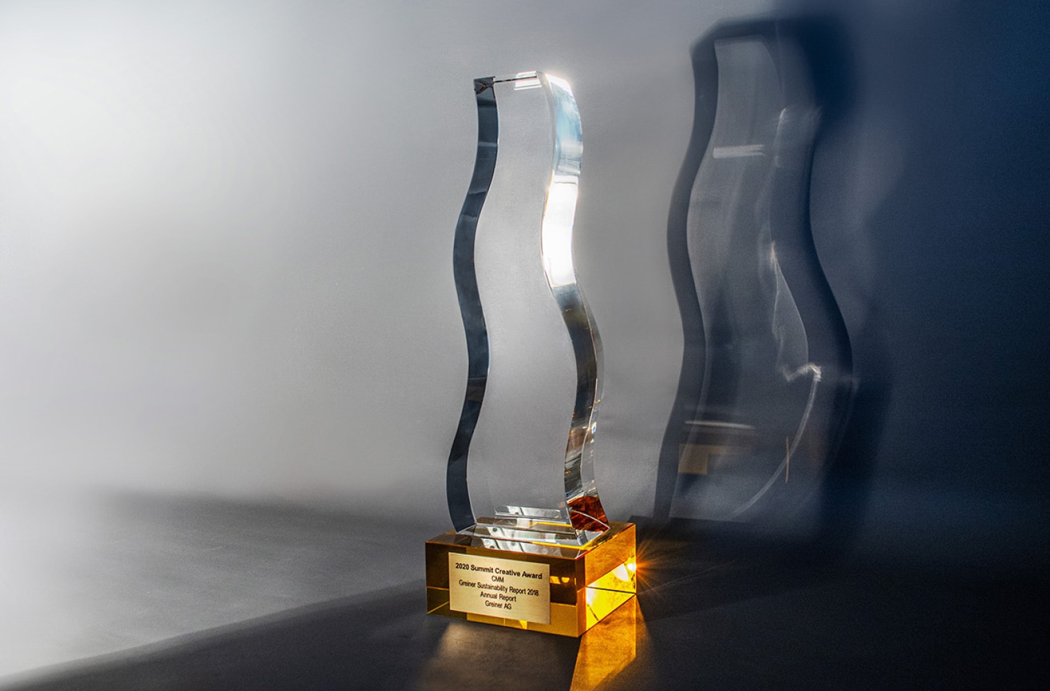 Trophäe mit leuchtend gelbem Sockel aus Glas wird von einer Seite angeleuchtet
